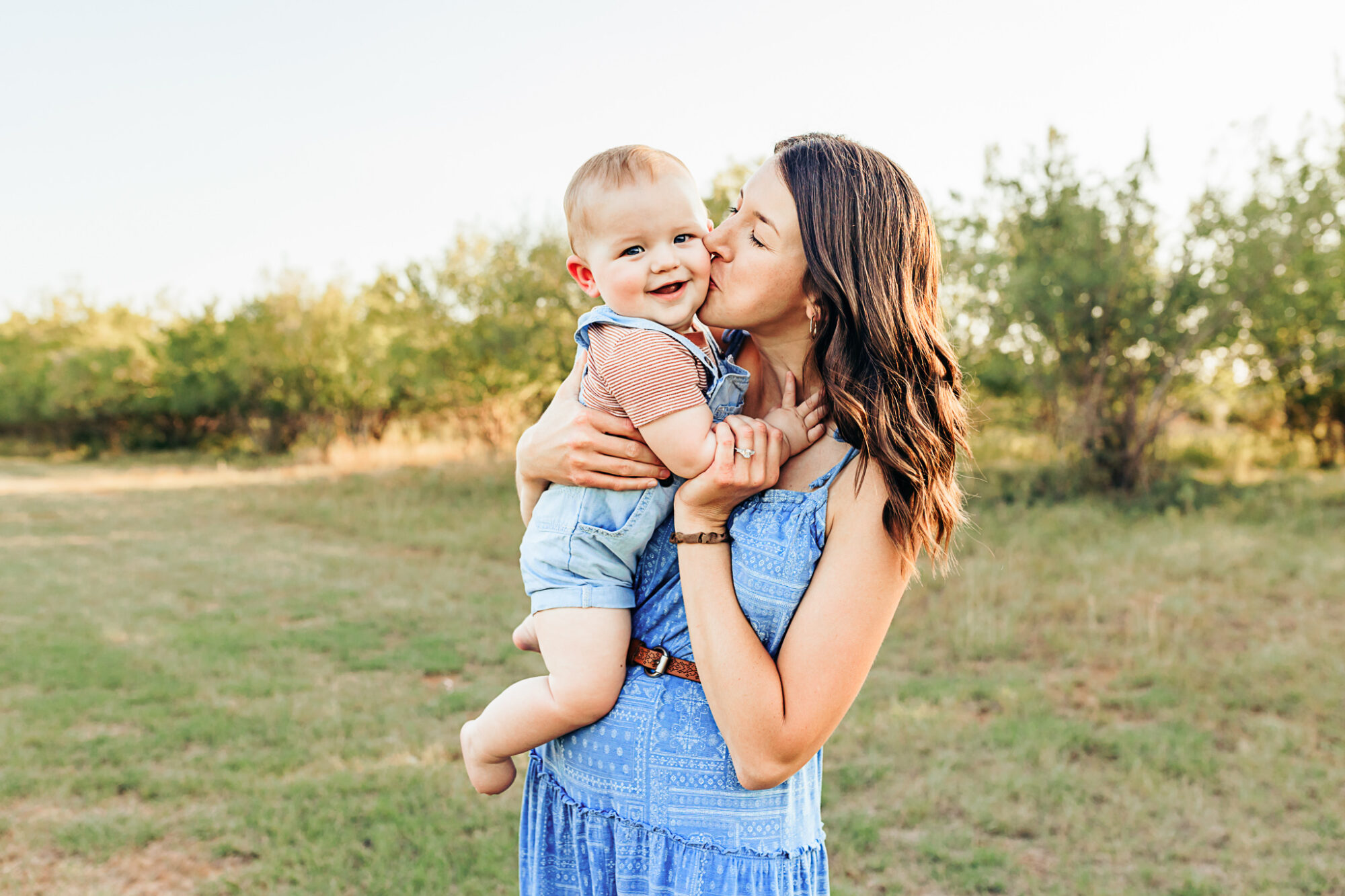 A young mom holds her son during their family photo session by OKC family photographer Charis Elisabeth Photography at Lake Hefner, OKC.