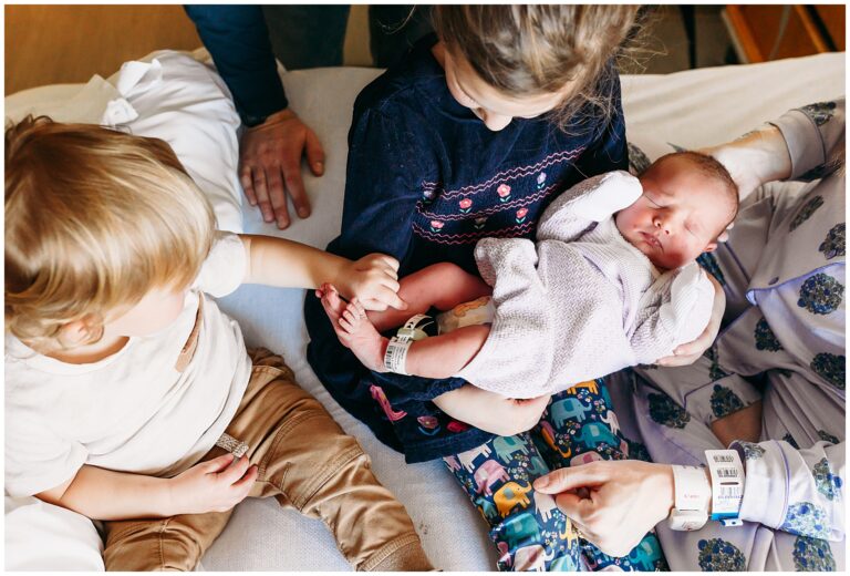 Little brother looks at new baby sister.