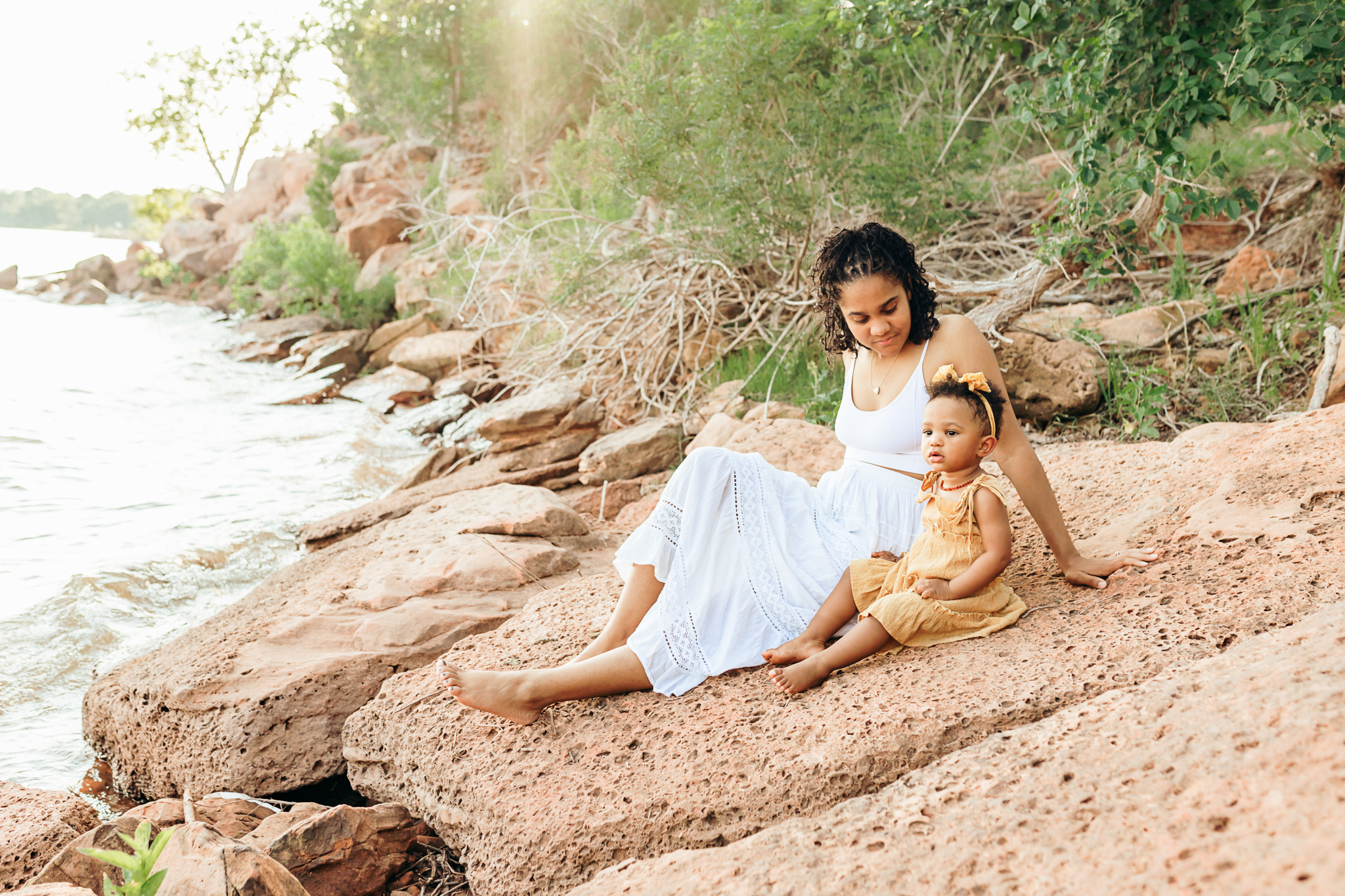 Mom and daughter sit at the lake during photo session.