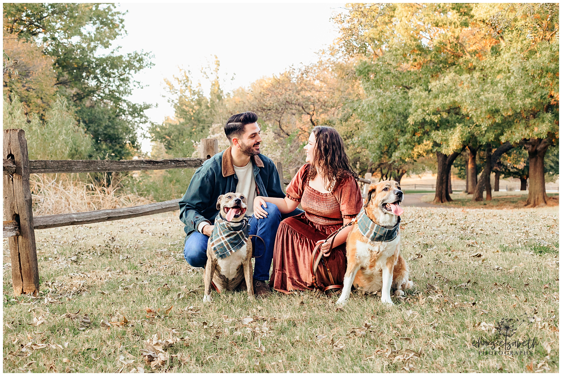 A couple sits with dogs in fall setting in Edmond, OK.