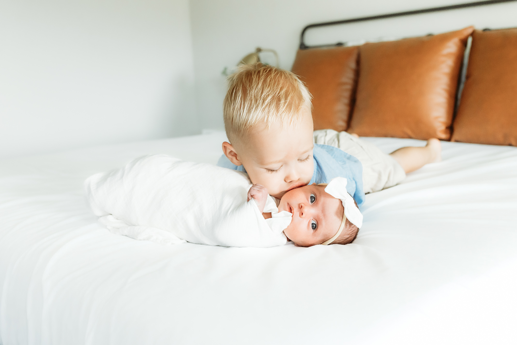 Brother kisses baby sister.