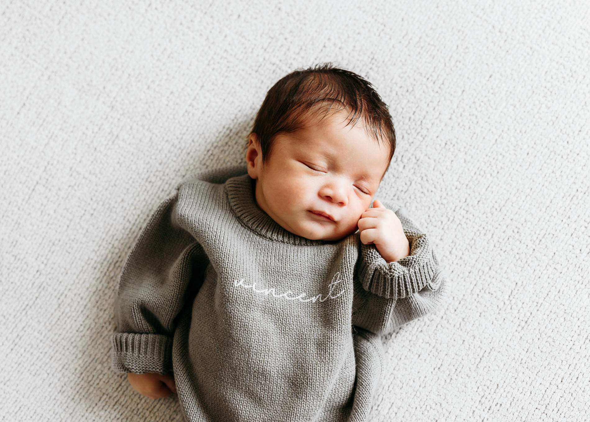 Newborn baby portrait in green sweater.